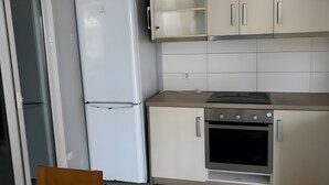 A kitchen with a refrigerator, oven, and cabinets.