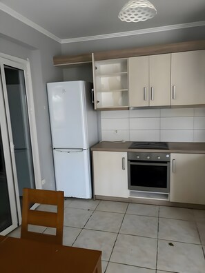 Eine Küche mit Kühlschrank, Backofen und Schränken.