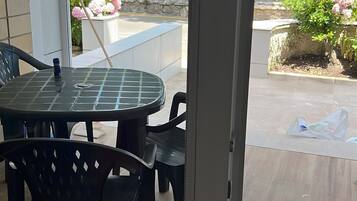 Een kamer met een glazen deur die uitkomt op een balkon met uitzicht op het strand en palmbomen.