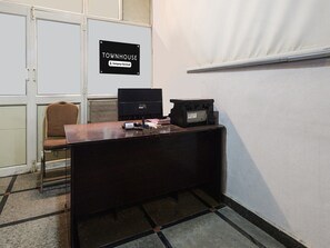 Ein Büro im Eckbereich mit Schreibtisch, Computer und Drucker, einem Stuhl und einem Schild, das es als vom Unternehmen betreutes Reihenhaus kennzeichnet.