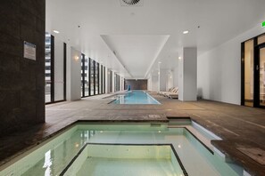 Ein langer, überdachter Pool mit Panorama-Glaswänden, gefliestem Boden und einem Schild mit den Spa-Regeln.
