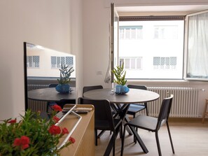 Un comedor moderno con una mesa redonda, sillas negras y plantas en macetas.