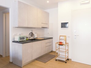 A compact kitchen with a toaster, sink, and a small cart with a basket. - At Francesca's House - Balduina 88 (Roma)