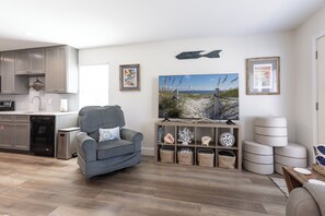 Ein modernes Wohnzimmer mit einem grauen Sofa, einem Strandbild und einer Holzkassette mit Dekoration.