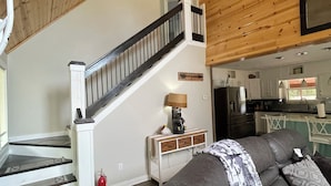 Un intérieur moderne avec un escalier, un espace de vie doté d’un canapé et une cuisine en arrière-plan.