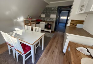 Une cuisine compacte avec un coin repas, un plancher en bois et une vue sur l’espace de vie.