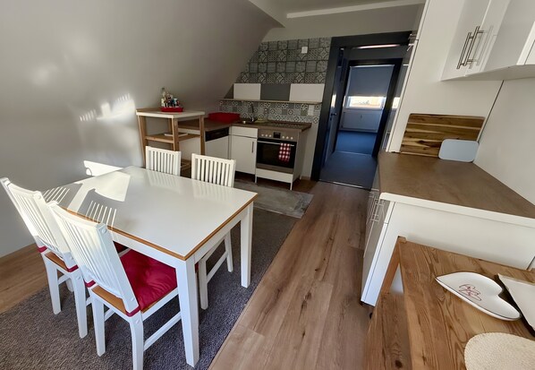 Eine kleine Küche mit Essbereich, Holzböden und Blick in den Wohnraum.