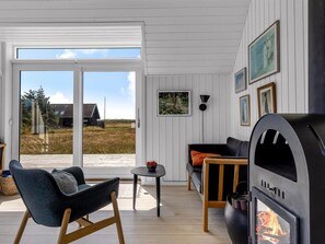 Ein modernes Wohnzimmer mit Kamin, einer Couch, einem Sessel und einem Tisch.