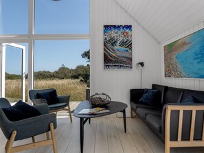 Ein modernes Wohnzimmer mit großem Fenster, zwei Sofas, einem Couchtisch und Bildern an den Wänden.