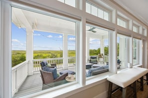 A covered porch with large windows, wicker furniture, and a bench. - Oyster Manor|Marsh Views|Heated Pool+Spa|Vilano Beach (St. Augustine)