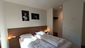 A hotel room with a large bed, bedside lamps, and two framed pictures on the wall. - L-cube Hottub 4+2 (Maarn)
