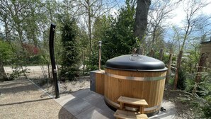 A wooden sauna with a bench and a chimney, surrounded by trees. - L-cube Hottub 4+2 (Maarn)