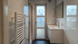 A narrow bathroom with a glass door, a towel rack, a sink, and a mirror. - L-cube Hottub 4+2 (Maarn)