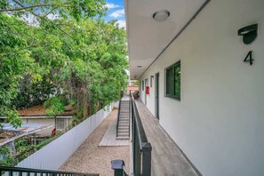 A narrow corridor with a staircase leading to an upper level, surrounded by greenery and a white building with the number 4. - West Brickell #4 Free Parking & Renovated 2BR (Miami)