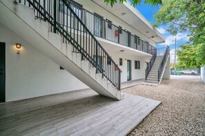 Ein modernes Gebäude mit Treppe, einer Holzterrasse und einem Kiesbereich.