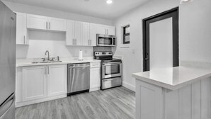 A modern kitchen with white cabinets, stainless steel appliances, and a wooden floor. - West Brickell #3  Minutes to Downtown Miami (Miami)