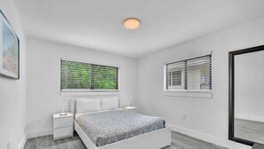 A bedroom with a bed, two bedside tables, a nightstand, a window with blinds, and a ceiling light. - West Brickell #3  Minutes to Downtown Miami (Miami)