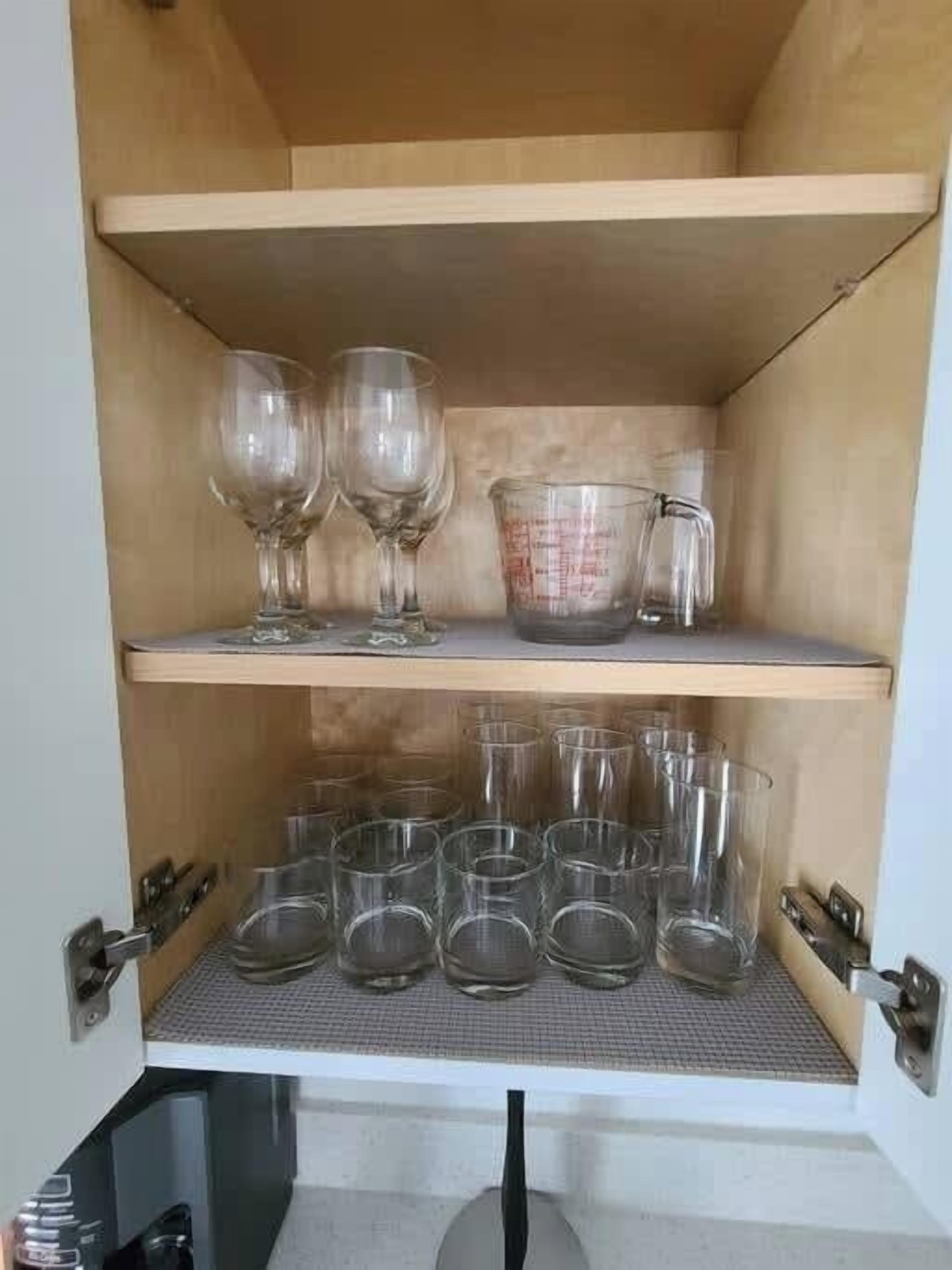 Un meuble en bois doté d’étagères où sont rangés des verres transparents et un verre doseur.
