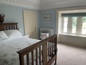 Ein Schlafzimmer mit einem hölzernen Bett, einer weißen Tür, einem Fenster mit Blick und einer Heizung.