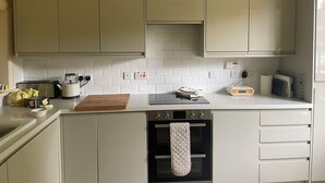 Eine Küche mit weißen Schränken, einem Toaster, einem Wasserkocher und einem Radio. Zwei Pendelleuchten sind angebracht.