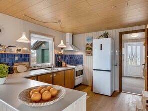 Eine moderne Küche mit einem weißen Kühlschrank, Holzschränken, einer blauen Fliesenrückwand und einem Fenster mit Blick.