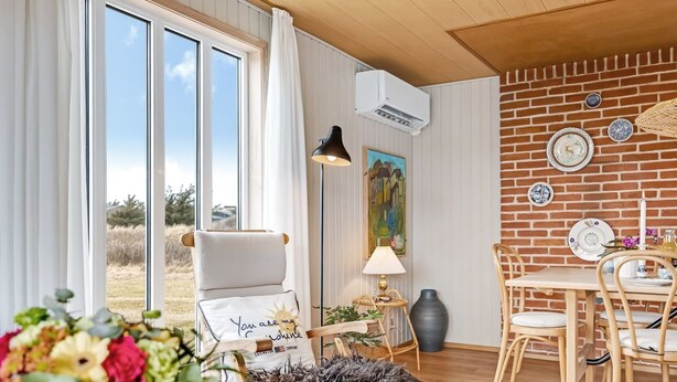 A room with a large window, a chair with a cushion, a table with chairs, a lamp, and a painting on the wall. - "Sida" - 400m from the sea by Interhome (Løkken)