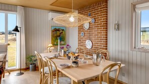 A dining area with a wooden table, chairs, a hanging light fixture, and a brick wall with decorative plates. - "Sida" - 400m from the sea by Interhome (Løkken)