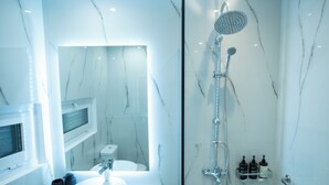 Une salle de bain moderne avec un lavabo en marbre, une douchette à main et une cabine de douche en verre.