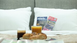 Un llit amb almoades blanques, un carretó de l'esmorzar amb croissants i un got de suc, i dues guies de viatge sobre les almoades.