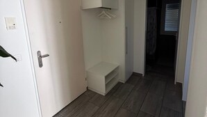 Ein Flur mit einer weißen Tür, einem weißen Kleiderschrank und einer kleinen Regalwand.