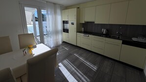 Eine moderne Küche mit Essbereich, großen Fenstern und Blick ins Freie.