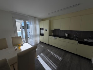 Een moderne keuken met een eethoek, grote ramen en uitzicht op de omgeving.