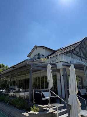 Een modern gebouw met een overdekt terras, een zwembad en een trap naar een balkon.