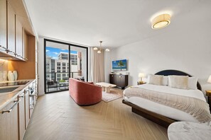 Ein modernes Hotelzimmer mit Bett, Sitzecke, Schreibtisch und Blick auf die Stadt.
