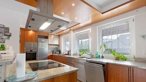 Una cocina moderna con armarios de madera, electrodomésticos de acero inoxidable, lavavajillas y un ventanal grande.