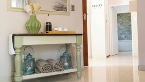 A hallway with a mirror, a console table with a vase, lanterns, and a door leading to another room. - Serene Holiday Retreat Near Hartbeespoort Dam (Hartbeespoort)