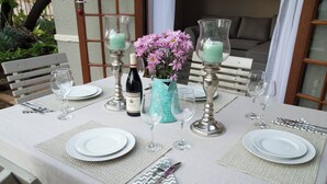 A table set for a meal with plates, cutlery, and glasses, a vase with flowers, and candles. - Serene Holiday Retreat Near Hartbeespoort Dam (Hartbeespoort)