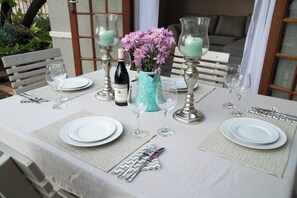 Une table mise pour un repas, avec des assiettes, des couverts et des verres, un vase rempli de fleurs et des bougies.