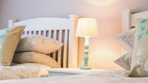A neatly made bed with a white headboard, a bedside table with a lamp, and several pillows. - Serene Holiday Retreat Near Hartbeespoort Dam (Hartbeespoort)
