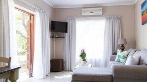 A well-lit living room with a sofa, a television, and a dining area with a table and chairs. - Serene Holiday Retreat Near Hartbeespoort Dam (Hartbeespoort)