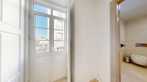 Un passadís amb una porta blanca que dona a un bany amb vàter i un cisteller.