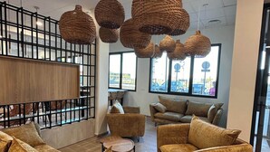 Un interior moderno con lámparas colgantes de mimbre, un separador de madera y un mobiliario cómodo.