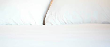 Una cama con ropa de cama y almohadas blancas.