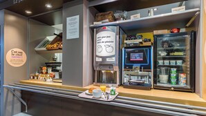 A breakfast counter with a coffee machine, a refrigerator with dairy products, and a tray with a croissant, coffee, and juice.