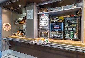 A breakfast counter with a coffee machine, a refrigerator with dairy products, and a tray with a croissant, coffee, and juice. - B&B Hotel Tours Nord 1 Val-De-Loire (Tours)