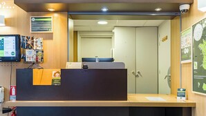 A reception desk with a computer monitor, a fire extinguisher, and informational posters on the wall.