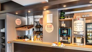 Un comptoir de café avec une machine à café, un tableau affichant le menu et une présentation de grains de café.