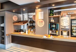 A café counter with a coffee machine, a menu board, and a display of coffee beans. - B&B Hotel Nantes Parc Expos La Beaujoire (Nantes)