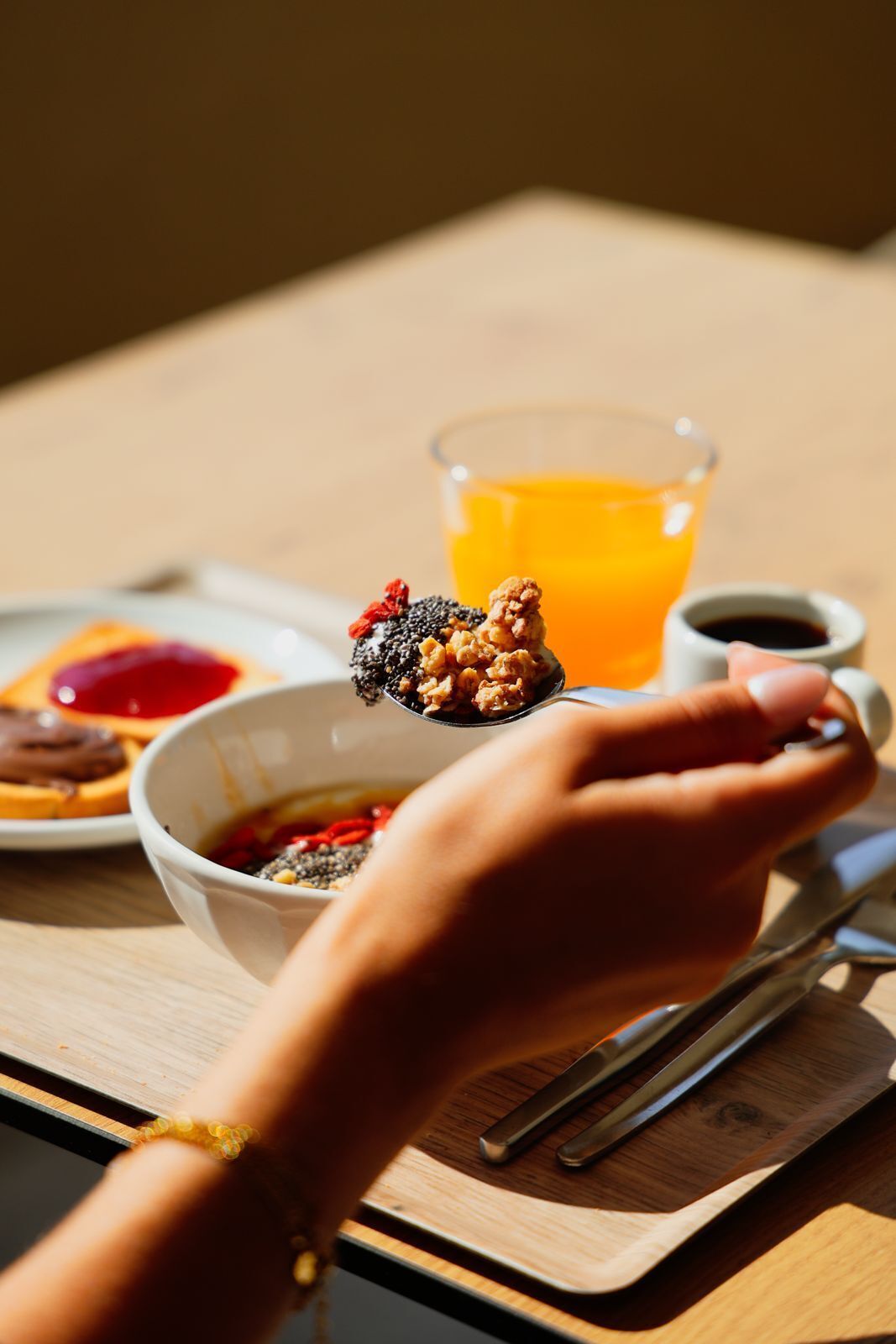 Una bandeja de desayuno con un tazón de cereal, un vaso de jugo de naranja y una taza pequeña de café.
