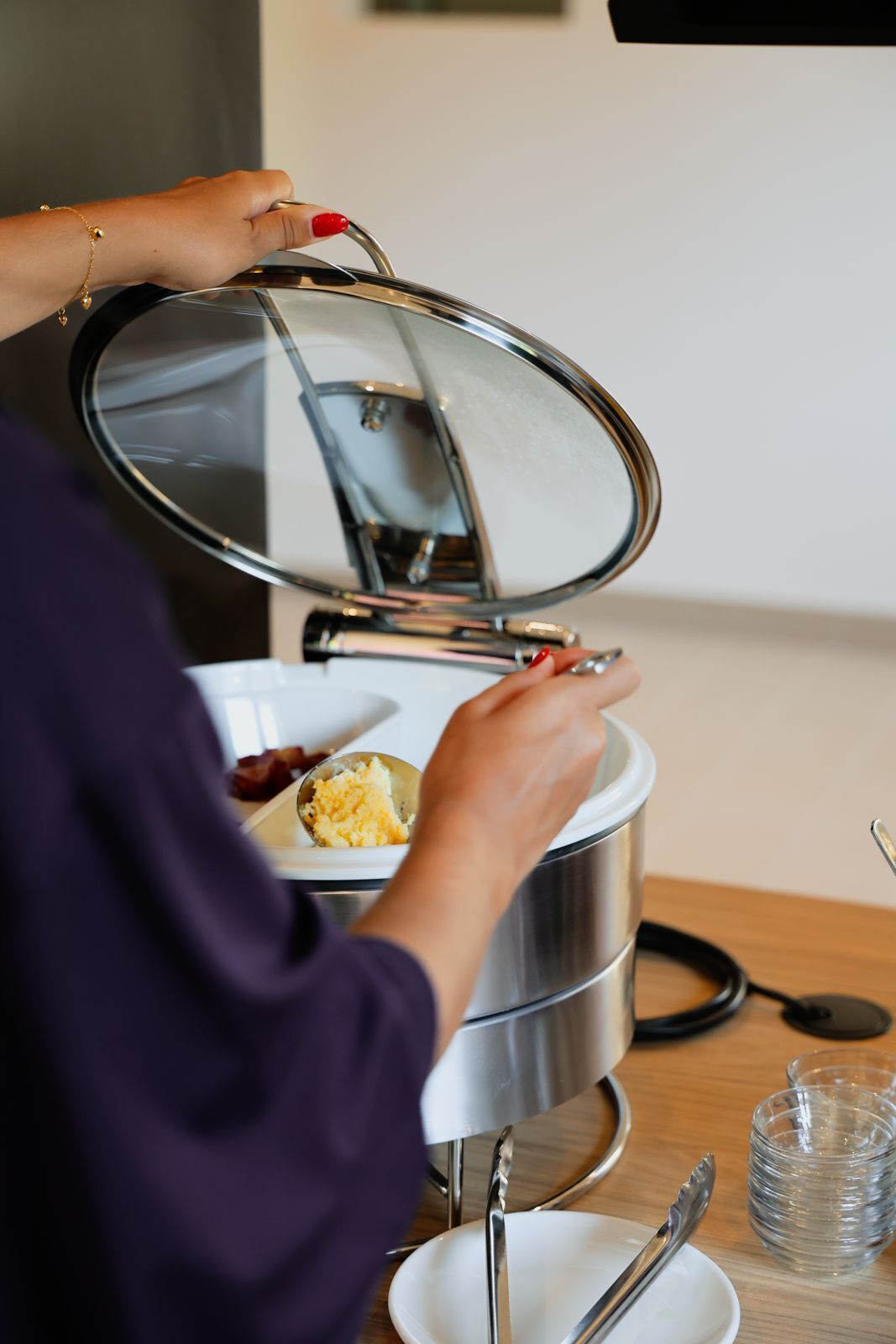 A person opening a stainless steel food container with a lid.